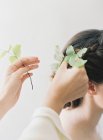 Hands adding leaves to braided updo — Stock Photo