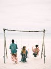 Wooden swing with three people — Stock Photo