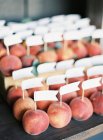 Fresh peaches with flags labels — Stock Photo