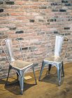 Металлические стулья по кирпичной стене — стоковое фото