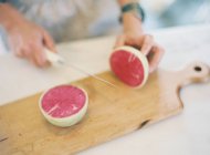 Donna tagliando formaggio sul tagliere — Foto stock