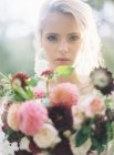 Braut steht mit Blumenstrauß — Stockfoto