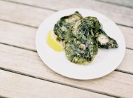 Моллюски с ломтиком лимона на тарелке — стоковое фото