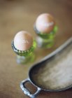 Boiled eggs in green egg-cup — Stock Photo