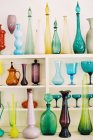 Garrafas coloridas e vasos em prateleiras de madeira — Fotografia de Stock