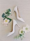 Біле взуття на високих підборах та квіти — стокове фото