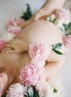 Pregnant woman covered with peonies — Stock Photo