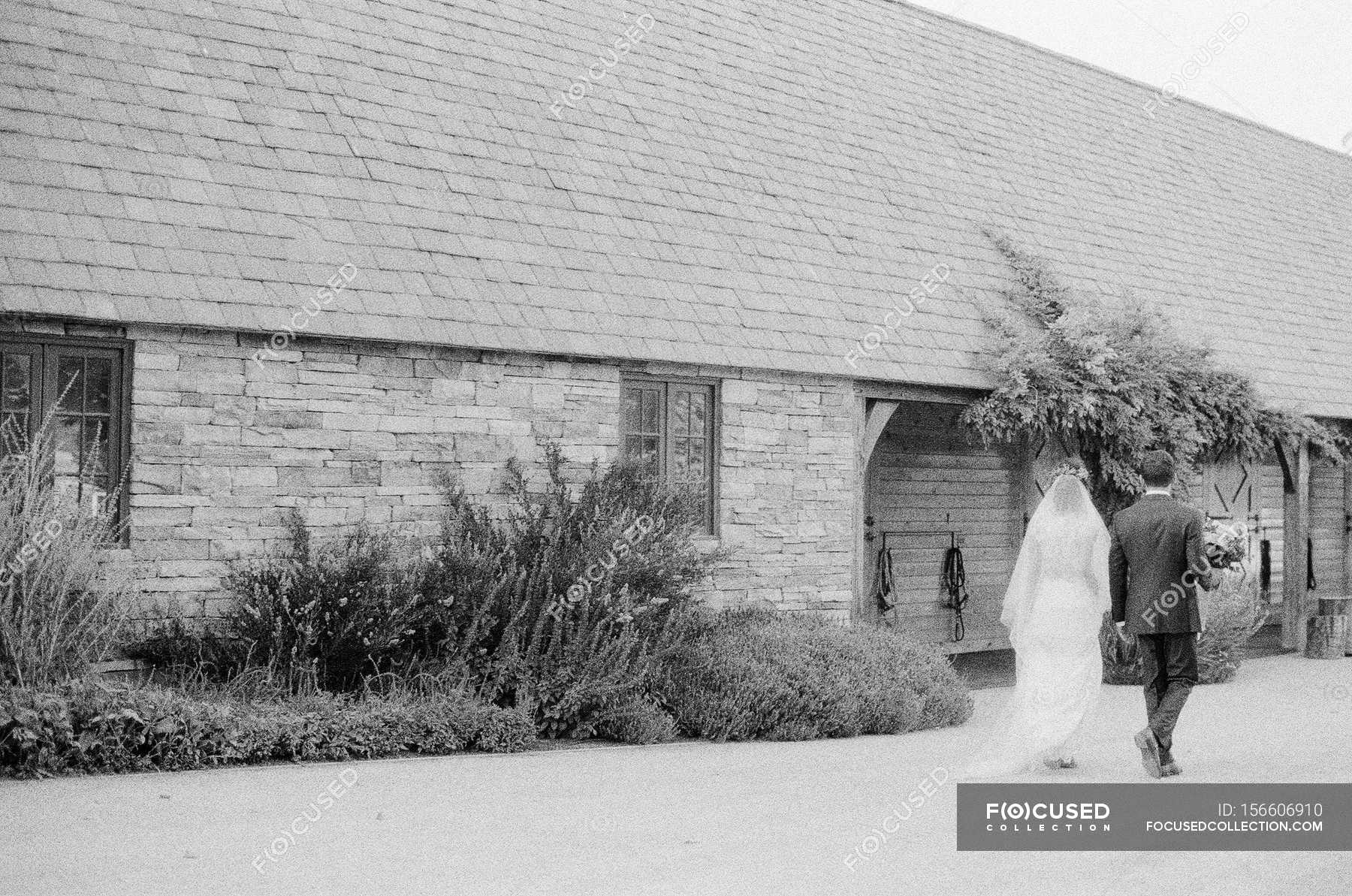 newlyweds-walking-hand-in-hand-family-ties-rear-stock-photo