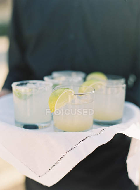 Hands holding tray with lemonade — Stock Photo