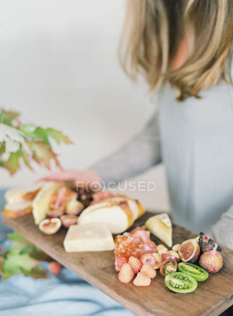 Donna che tiene bordo con formaggio e frutta — Foto stock