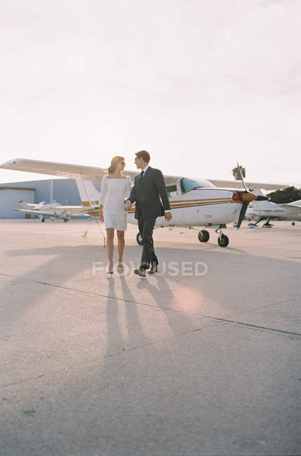 Casal andando de mãos dadas no aeródromo — Fotografia de Stock