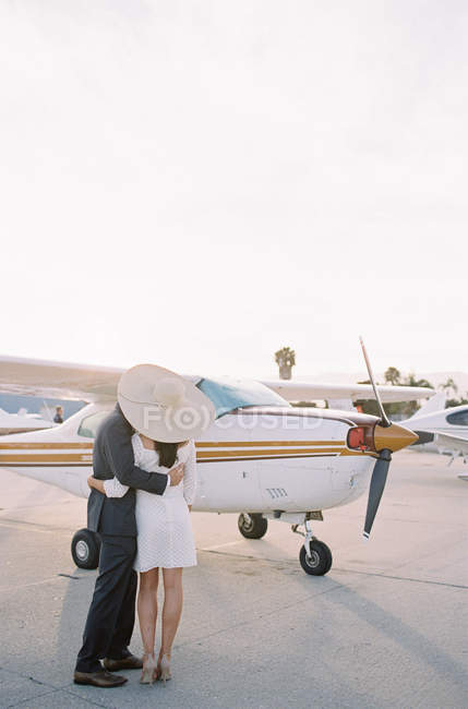 Молодая пара обнимается рядом с самолетом — стоковое фото