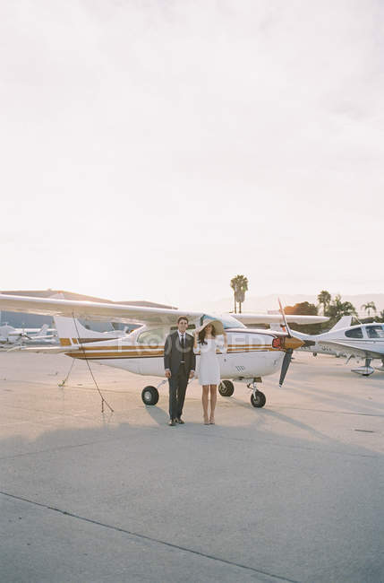 Пара, стоящая рядом с маленьким самолетом — стоковое фото