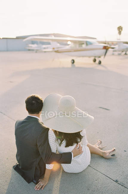Jeune couple assis sur le tarmac — Photo de stock