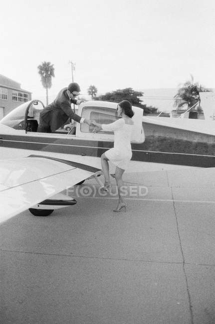 Чоловік допомагає жінці вилітати з літака — стокове фото