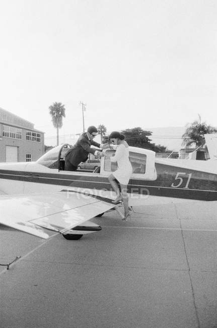 Чоловік допомагає жінці вилітати з літака — стокове фото