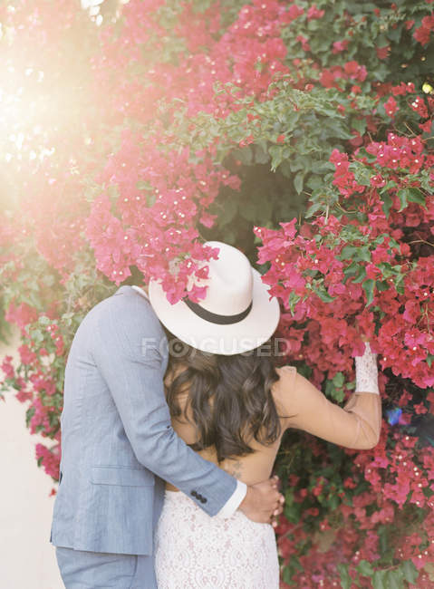 Joven pareja abrazando y oliendo flores - foto de stock
