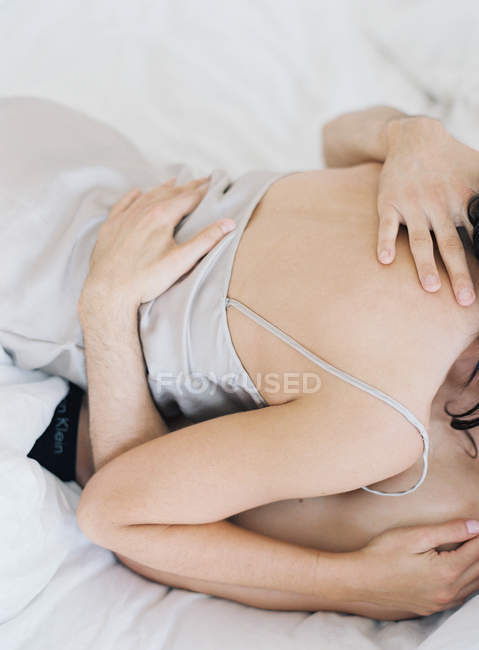 Jeune couple étreignant au lit — Photo de stock