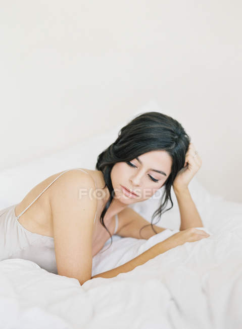 Jeune femme allongée au lit — Photo de stock