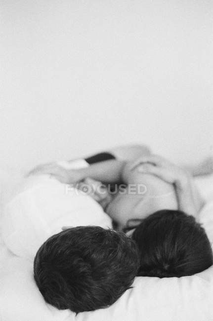 Hombre y mujer abrazándose en la cama - foto de stock