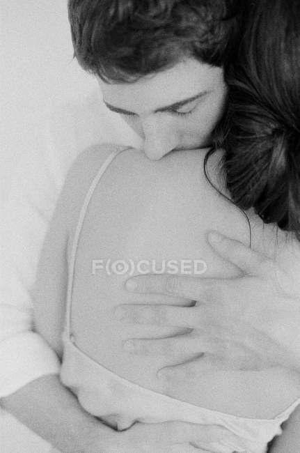 Man embracing woman and kissing shoulder — Stock Photo