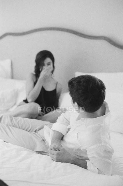 Homme allongé sur le lit et regardant la femme — Photo de stock