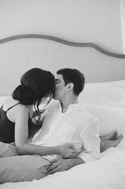 Homem e mulher beijando e deitado na cama — Fotografia de Stock