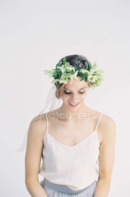 Mujer con corona de flores mirando hacia abajo - foto de stock