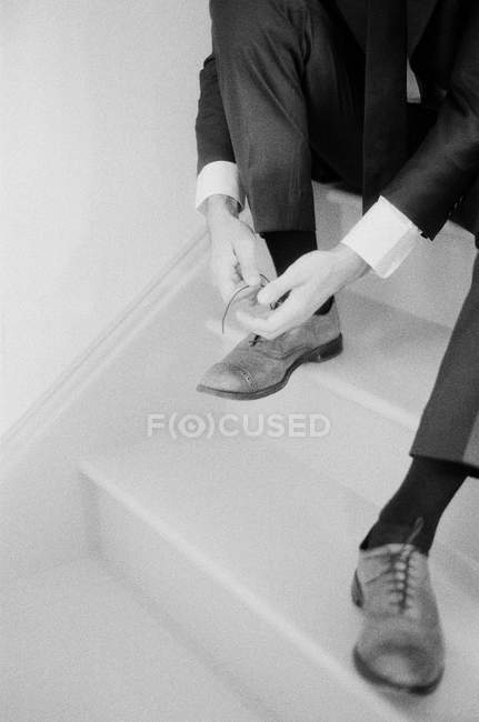 Мужчина сидит на лестнице и завязывает шнурки — стоковое фото