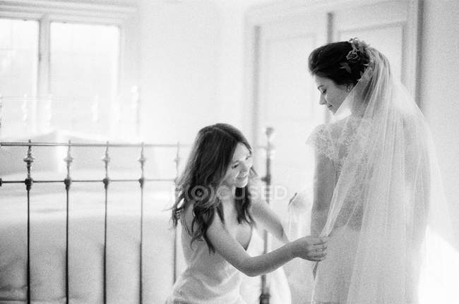 Женщина помогает невесте с свадебным платьем — стоковое фото