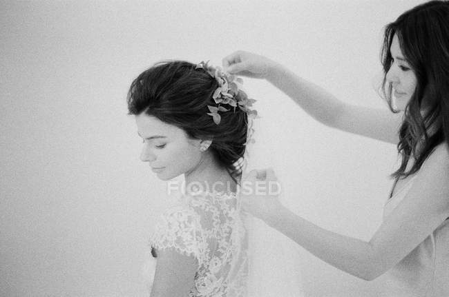 Woman helping bride with hair decoration — Stock Photo