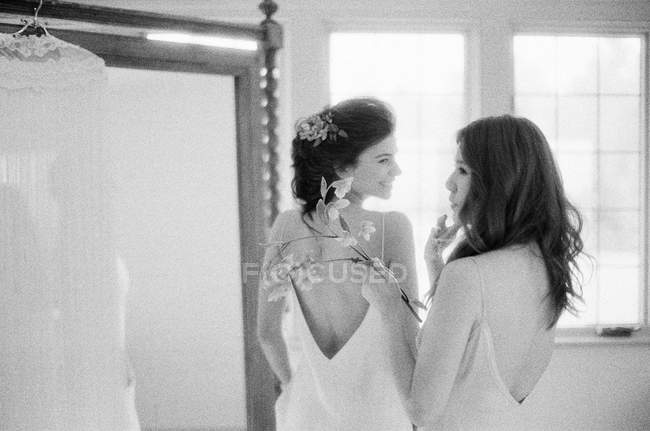 Bridesmaid helping bride with wedding dress — Stock Photo
