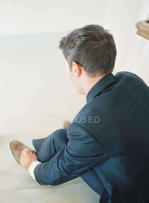 Man sitting on stairs and tying shoelaces — Stock Photo