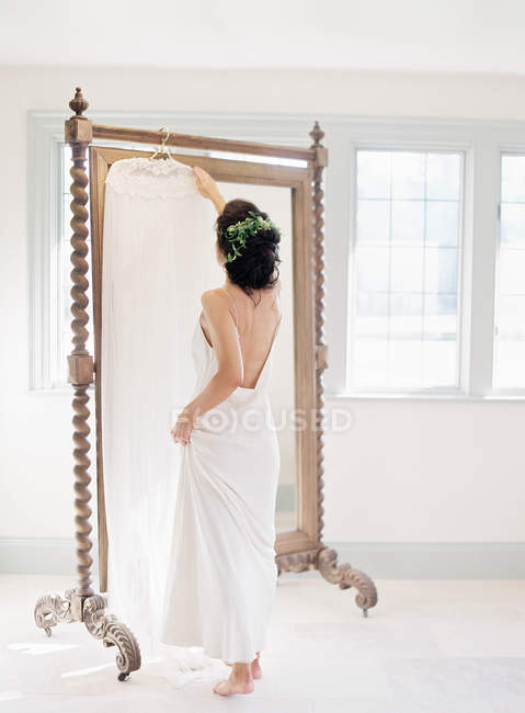 Frau nimmt Hochzeitskleid aus Spiegel — Stockfoto