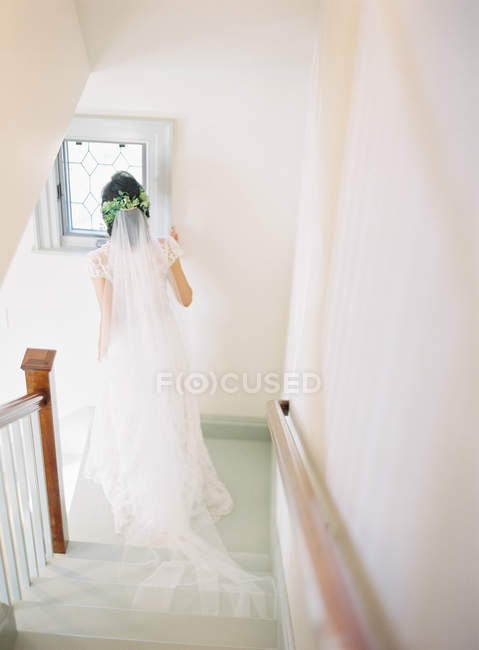Женщина в свадебном платье стоит на лестнице — стоковое фото