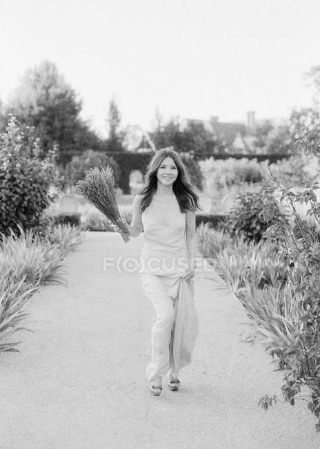 Donna con fiori che corrono lungo il sentiero — Foto stock