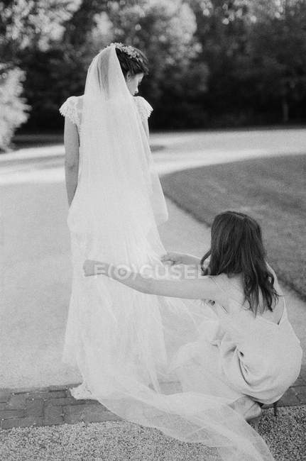 Bridesmaid helping bride with veil — Stock Photo