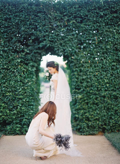 Mujer con flores ayudando novia - foto de stock