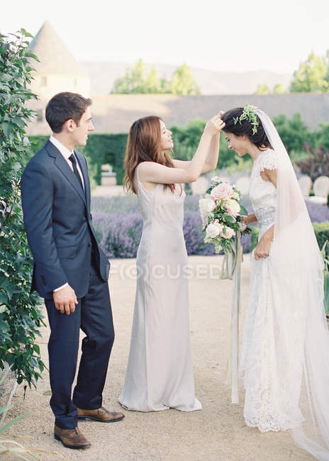 Bridesmaid helping bride with wreath — Stock Photo