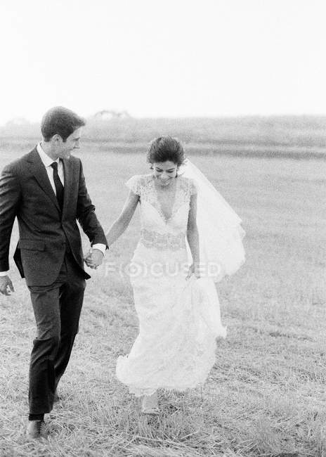 Couple nouvellement marié marchant dans le champ — Photo de stock