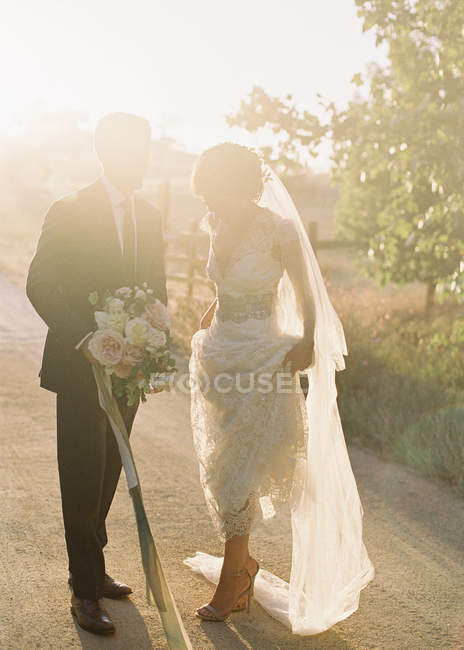 Groom and bride standing outdoors — Stock Photo