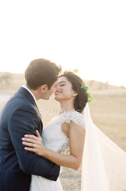 Pareja recién casada abrazos y besos - foto de stock