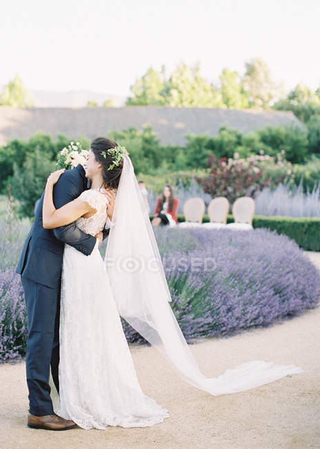Bräutigam umarmt Braut im Garten — Stockfoto