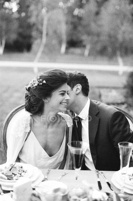 Recém-casados beijando na mesa de casamento — Fotografia de Stock