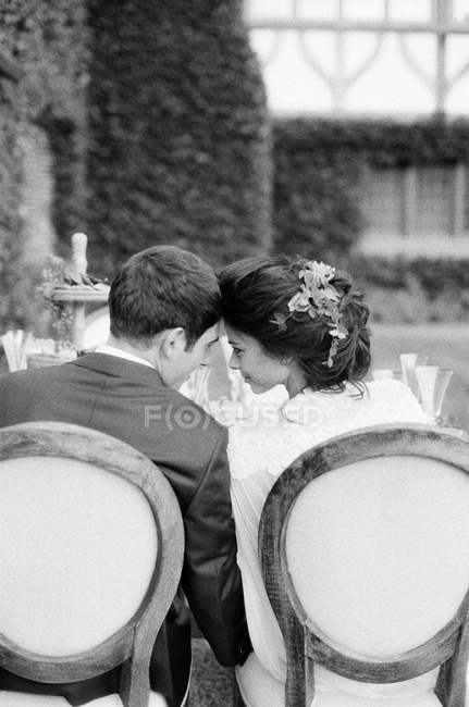 Noivo e noiva sentado cabeça a cabeça — Fotografia de Stock