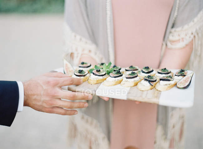 Woman holding appetizers on wooden board — Stock Photo