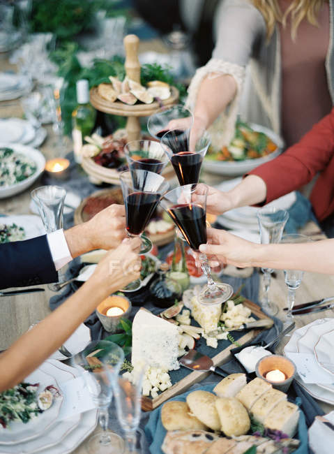 People clincking glasses at setting table — Stock Photo