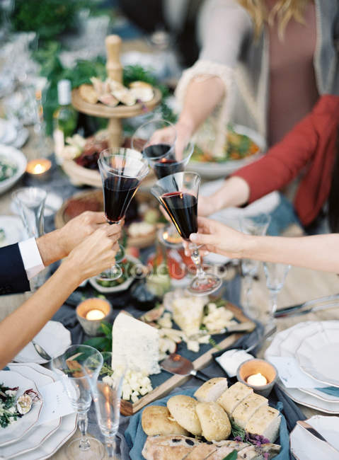 People clincking glasses at setting table — Stock Photo