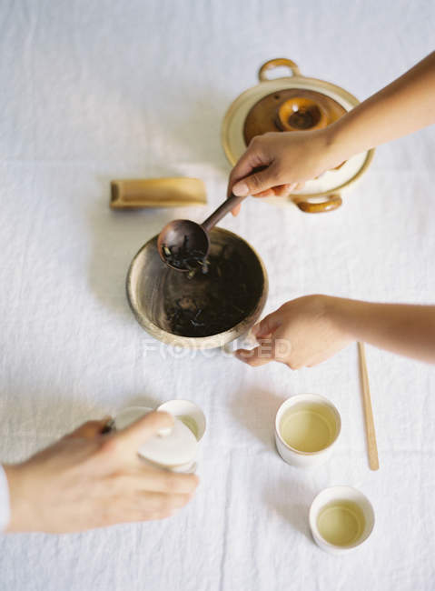 Руки беруть чайне листя з миски — стокове фото