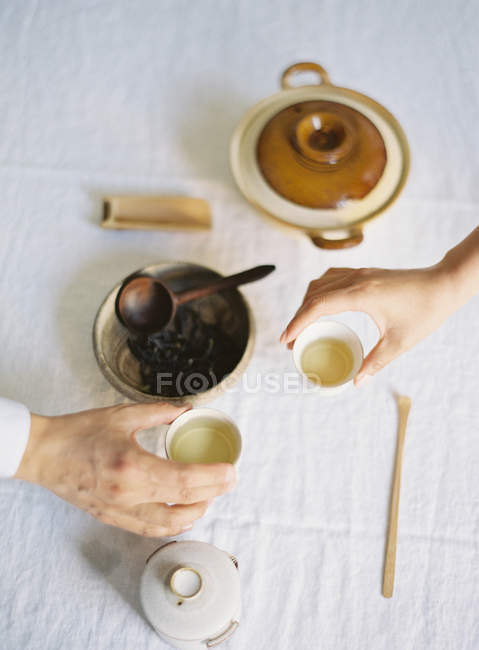 Hands holding cups with green tea — Stock Photo